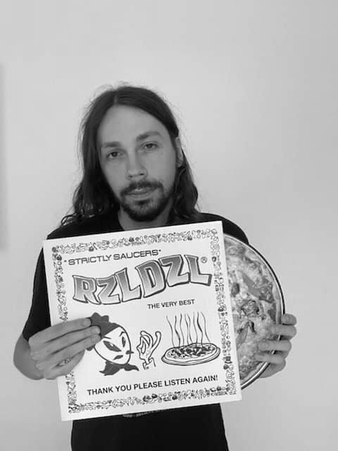 Mężczyzna trzyma płytę RZL DZL - "Strictly Saucers".