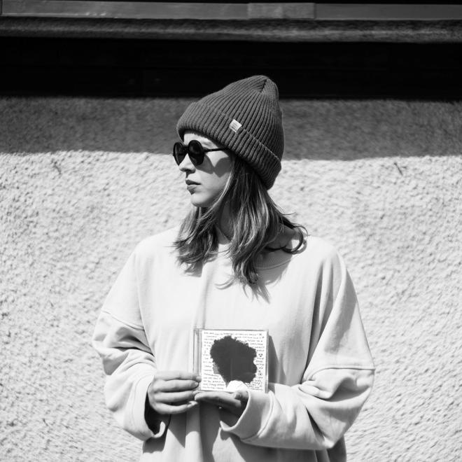 Zdjęcie Seeme, która trzyma płytę Erykah Badu - "Worldwide Underground". Artystka patrzy na lewo.